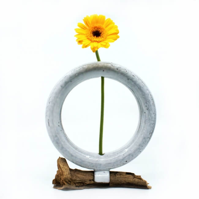 Handgemachte zirkulaere weiße Vase mit Treibholz - mit Blume